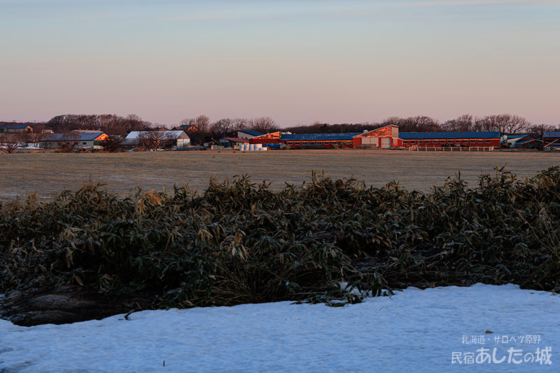 牧場の建物を赤く照らす光